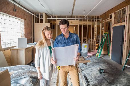 deux personnes regardent des plans dans une maison en construction